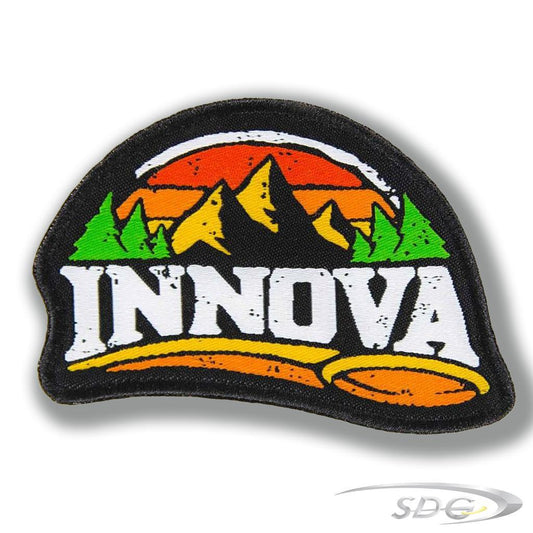 Innova Mountain Patch with Mountains and Trees against a gradient sky, the word Innova written in bold white lettering and a flying disc golf disc across the bottom of the patch 