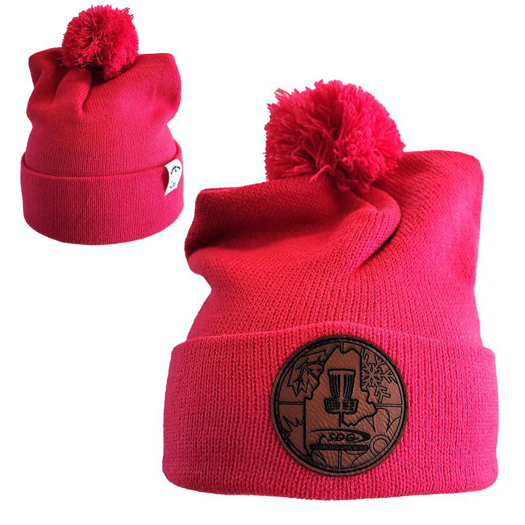 Pink Raspberry Colored Knit Pom Pom Beaning with SDG Sabattus Disc Golf Laser Engraved on leather patch that is sewn to the front of the hat, also a back view of the hat with the Rogue Life Maine logo on a small white tag sewn to the hat rim