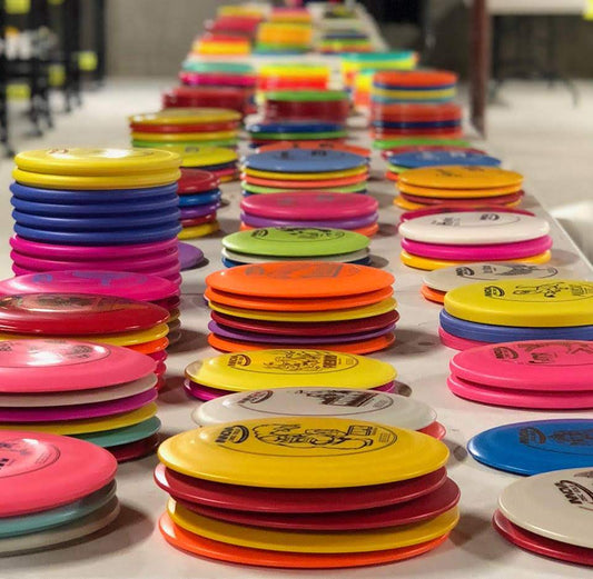 Stacks of vibrant colored disc golf discs - stretched out on a table into the distance