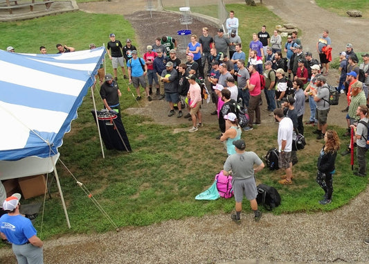 disc golfers grouped around nate sexton at the sexton shootout in 2019 at sabattus disc golf