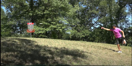 Paul McBeth wearinga  pink shirt putts into a disc golf basket at the 2018 DGLO for a score of -18.