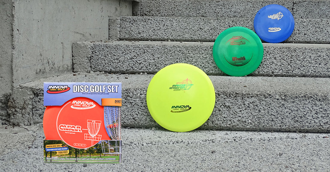 An Innova starter disc golf set on a set of steps with successive yellow, green, and blue discs going up the stone stairs.