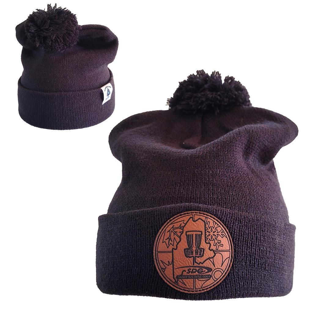 Black colored Knit Pom Pom Beaning with SDG Sabattus Disc Golf Laser Engraved on leather patch that is sewn to the front of the hat, also a back view of the hat with the Rogue Life Maine logo on a small white tag sewn to the hat rim 