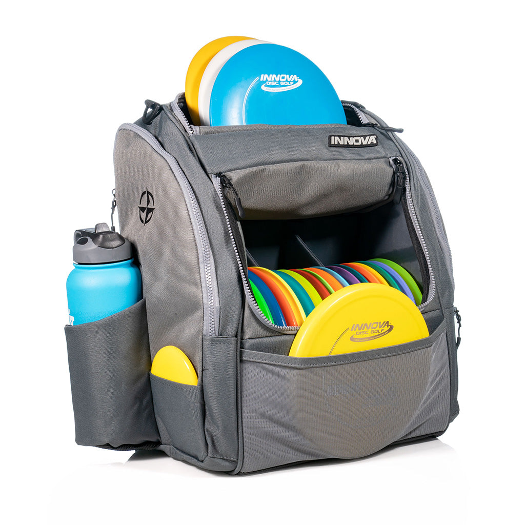 Innova Safari Pack Backpack Disc Golf Bags grey filled with an assortment of discs, mini marker & canteen
