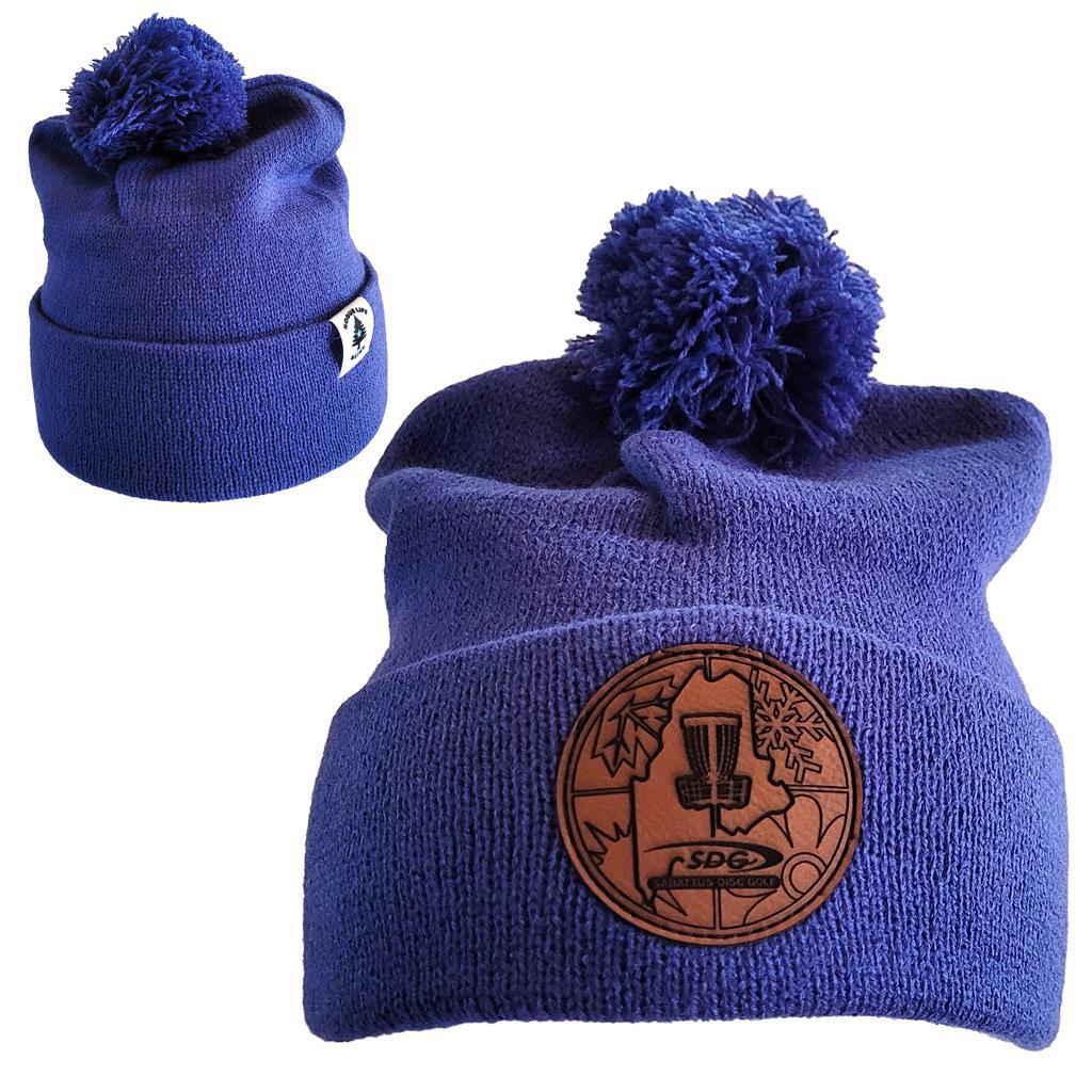 True Royal Knit Pom Pom Beaning with SDG crittercontrolcincinnati Laser Engraved on leather patch that is sewn to the front of the hat, also a back view of the hat with the Rogue Life Maine logo on a small white tag sewn to the hat rim 